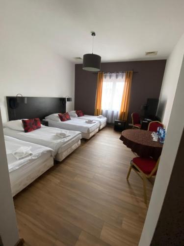 a hotel room with three beds and a table at Hotel Altamira in Piotrków Trybunalski