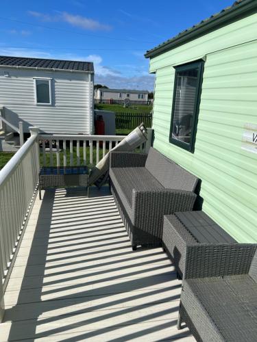 a deck with two benches and a house at Chrissys Caravan in Mablethorpe