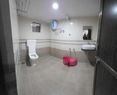 un bagno con un WC e un lavandino con due secchi rosa di Hotel New Rest Inn a Mahesāna