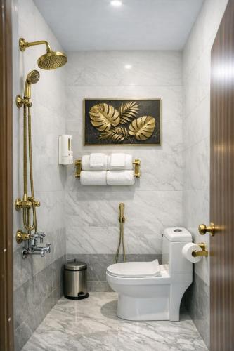 a bathroom with a toilet and a painting on the wall at Grand Maalyasa Hotel and Suites, US Consulate Hyderabad 2 Mins walk in Hyderabad