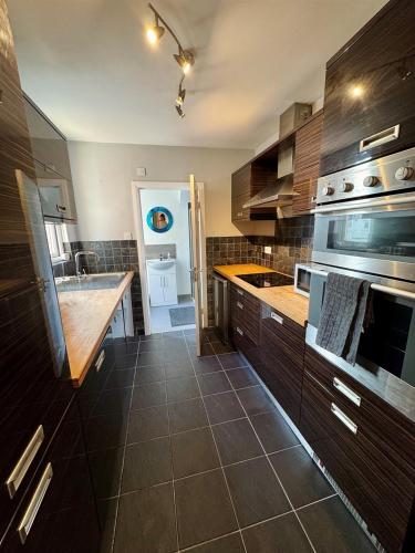 a kitchen with wooden cabinets and a counter top at Spacious 2 BR Flat in Gateshead - Free Parking in Gateshead