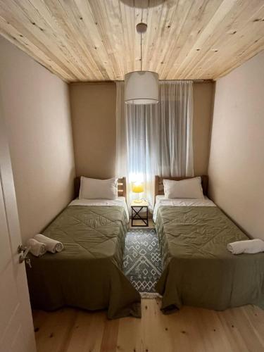 two beds in a small room with a window at Apartments Gabliani in Mestia in Mestia