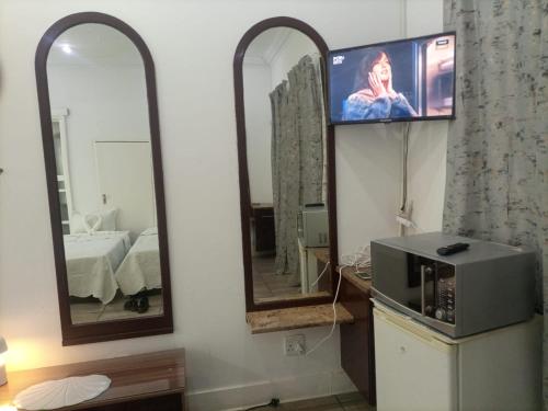a bathroom with two mirrors and a tv and a microwave at Zanem Guest House in Potchefstroom