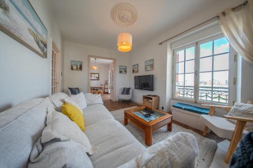 a living room with a couch and a large window at Villa authentique Vue mer 360 Les pieds dans l’eau in Larmor-Plage