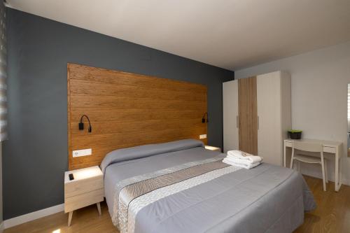 a bedroom with a bed and a wooden headboard at ALQUILAZ. Apartamentos Turísticos. in Zamora