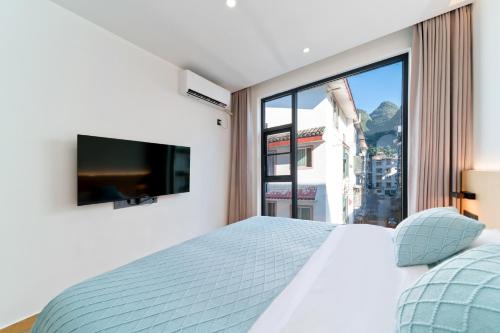 a bedroom with a bed and a large window at Yangshuo YeQi Hotel in Yangshuo