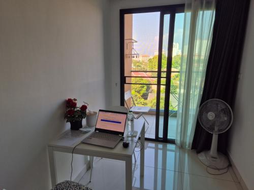 a laptop on a desk in a room with a balcony at Paradise Now in Jomtien Beach