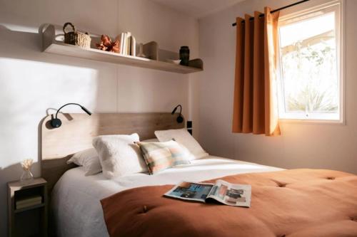 a bedroom with a bed with a magazine on it at ZEcamping 2 étoiles accès direct à la plage chiens acceptés piscine in Ghisonaccia