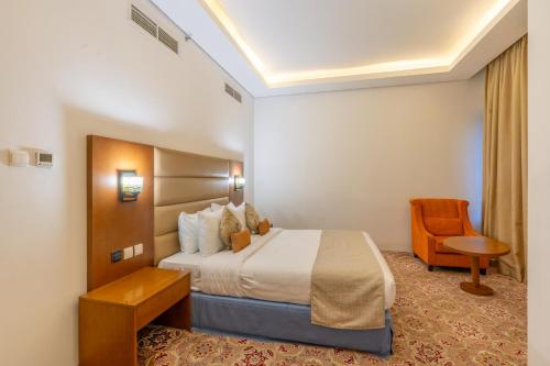 a hotel room with a bed and a chair at Tamr Inn Hotel in Dubai