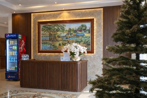 a christmas tree in a lobby with a painting on the wall at Sơn Lâm Hotel in Chợ Hiếu