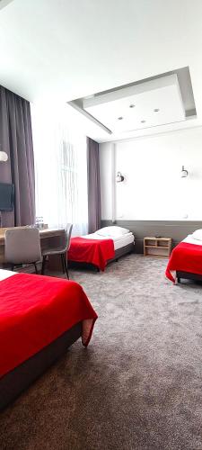 a hotel room with three beds with red sheets at Noclegi Sezam in Łańcut