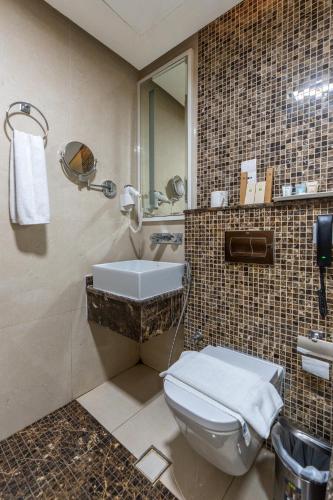 a bathroom with a toilet and a sink and a mirror at Tamr Inn Hotel in Dubai