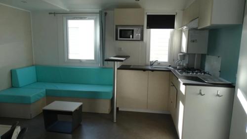 a small kitchen with a blue couch in a room at ZEcamping 4 étoiles chiens acceptés piscine chauffée et toboggans in Portiragnes