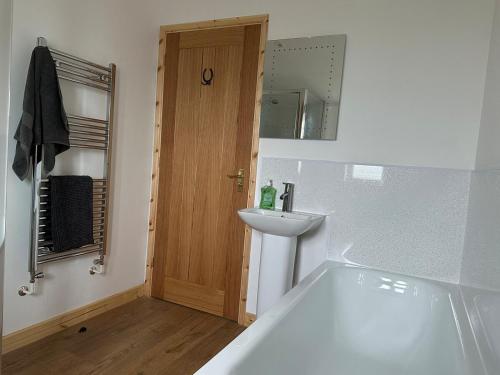 a bathroom with a tub and a sink and a mirror at The Apple Press in Williton