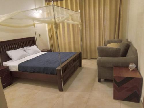 a bedroom with a bed and a couch and a chair at Marakunda - Victoria in Jinja