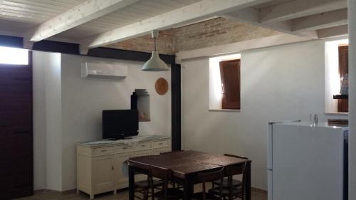 uma cozinha com uma mesa com cadeiras e uma televisão em Casa Vacanza Piazza Gramsci 1 em Scanzano Jonico