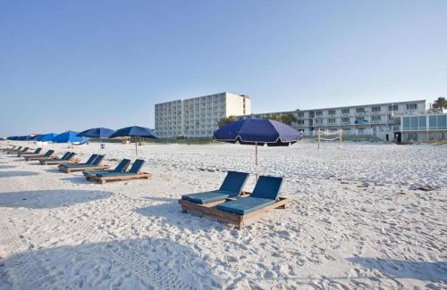 una fila de tumbonas y una sombrilla en una playa en Beachside West Townhome, en Panama City Beach