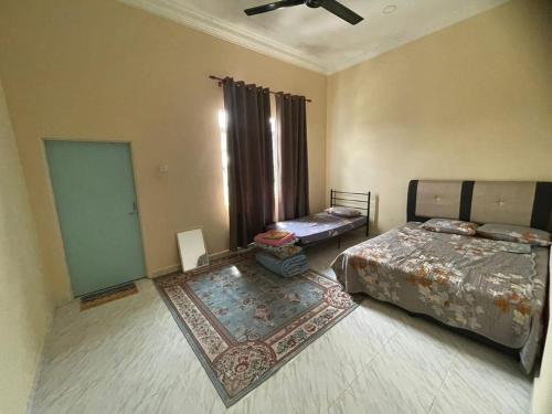 a bedroom with two beds and a rug at Ramly Homestay in Kuala Terengganu