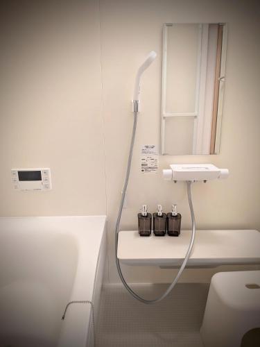 a white bathroom with a shower and a sink at とまり木 in Yoshino