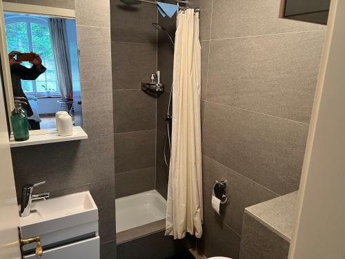 a person taking a picture of a bathroom with a shower at Studio im Naturschutzgebiet in Spreitenbach