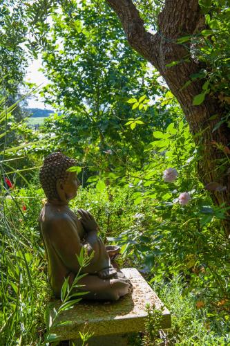 a statue sitting on a bench under a tree at Moinhos do Pisão in Povoa Dao