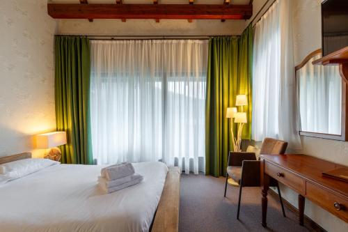 a hotel room with a bed and a desk and green curtains at Le Freudeneck in Wangenbourg