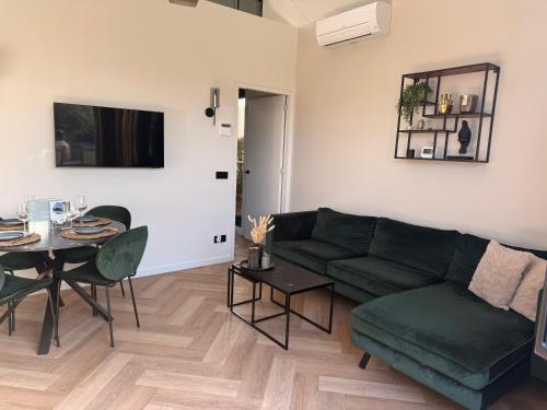 a living room with a green couch and a table at Cozy & Modern Tiny House in Velserbroek