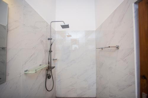 a shower in a bathroom with white marble walls at Palms shede Villa in Habaraduwa Central