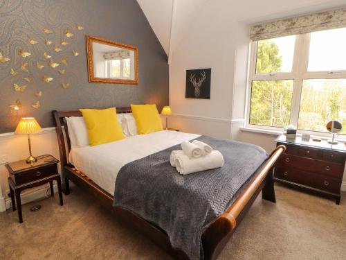 a bedroom with a bed with yellow pillows and a window at 1 Park Road in Windermere