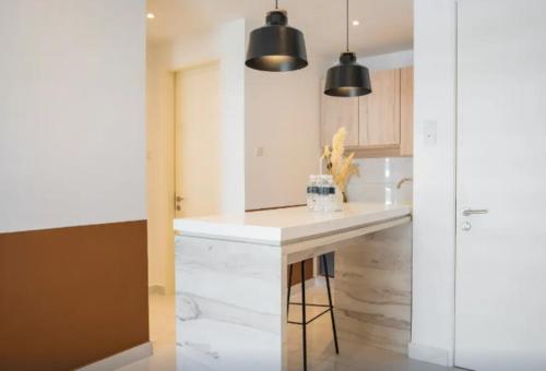 a kitchen with a white counter and black pendant lights at Inap II, Suterabay By Ayuhouz in Kota Kinabalu