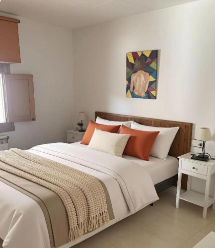 a bedroom with a large bed with orange and white pillows at Montrebei Casa González Apartamentos in Tolva