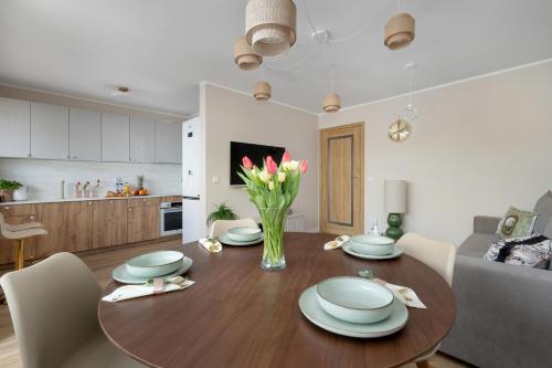 a dining room table with a vase of flowers on it at Marina Apartament Old Town View in Kamień Pomorski