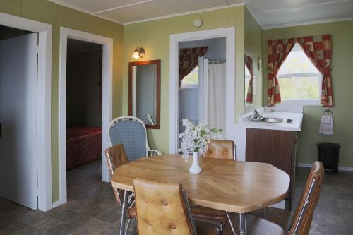 kuchnia i jadalnia z drewnianym stołem i krzesłami w obiekcie Motel Bellevue w mieście Rivière-du-Loup