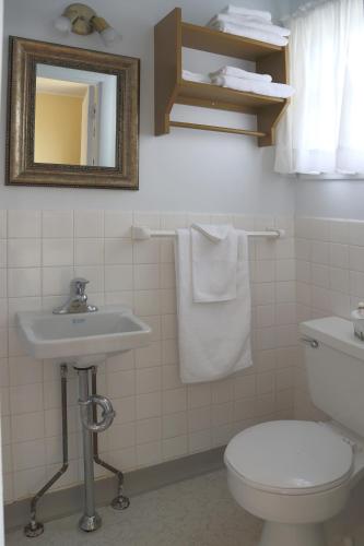 łazienka z toaletą, umywalką i lustrem w obiekcie Motel Bellevue w mieście Rivière-du-Loup