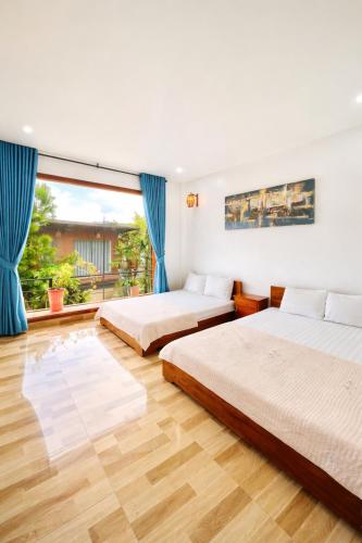 a bedroom with two beds and a large window at White Horse Homestay in Hue