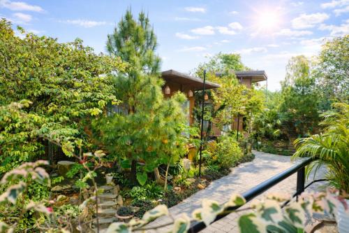 a garden with a house with trees and a walkway at White Horse Homestay in Hue