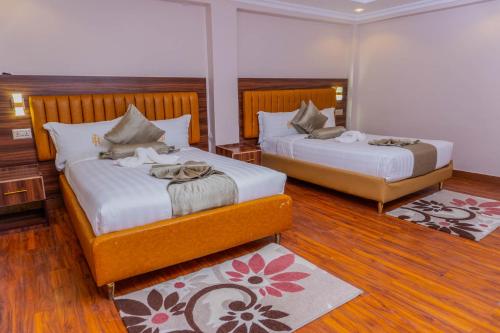 two beds in a room with wooden floors at Arise Sunshine Hotel in Narok