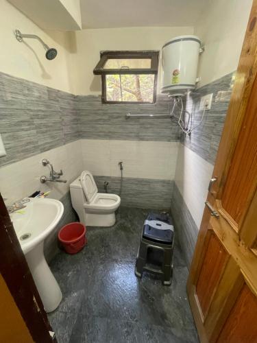 a small bathroom with a toilet and a sink at Sajjus Riverside Retreat in Manāli