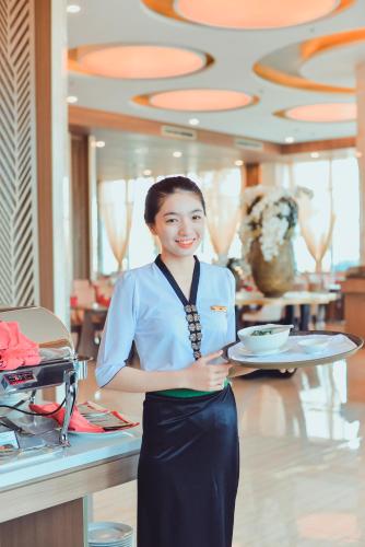 a woman is holding a plate in a restaurant at Muong Thanh Luxury Ca Mau Hotel in Cà Mau