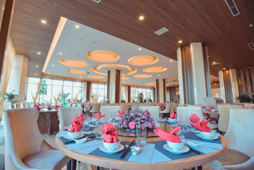 a dining room with a table with flowers on it at Muong Thanh Luxury Ca Mau Hotel in Cà Mau