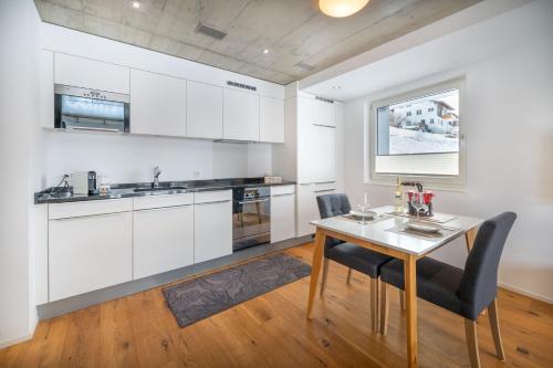 a kitchen with white cabinets and a table and chairs at Schwarzhornblick in Grächen