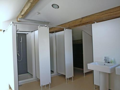 a bathroom with white stalls and a sink at mundoalbergue in Santiago de Compostela