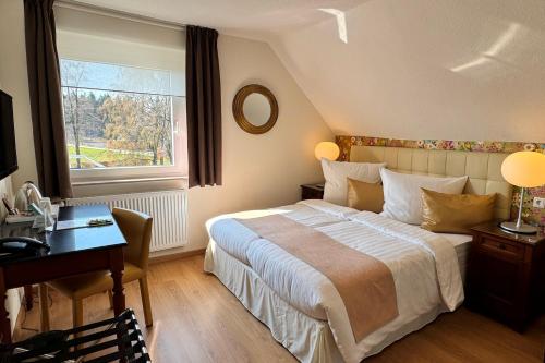 a bedroom with a bed and a desk and a window at Boutique Hotel Restaurant Hollerather Hof in Hellenthal