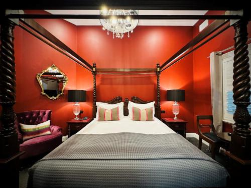 a bedroom with a bed with red walls and a chandelier at The Dudley Boutique Hotel in Daylesford