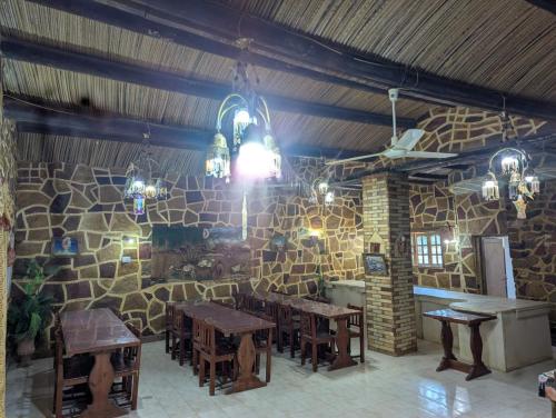 a dining room with tables and a stone wall at Old Oasis Hotel for Safari Trips in Az Zabū