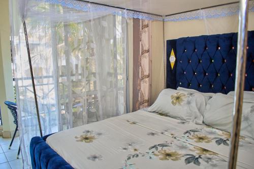 a bedroom with a bed with a blue headboard and a window at Razz Homes in Diani Beach