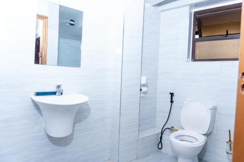 a white bathroom with a toilet and a sink at Arise Sunshine Hotel in Narok