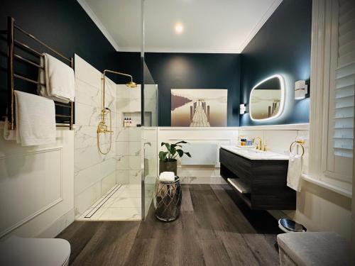 a bathroom with a tub and a sink and a mirror at The Dudley Boutique Hotel in Daylesford