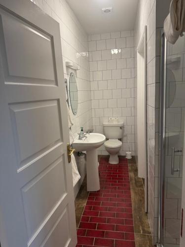 a white bathroom with a sink and a toilet at Waterfront Apartment in Dingle