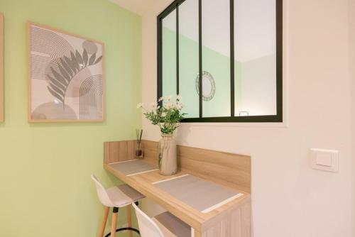a room with a desk with a window and a vase with flowers at Le Nid Vert - air conditioning - ground floor in Bourg-en-Bresse